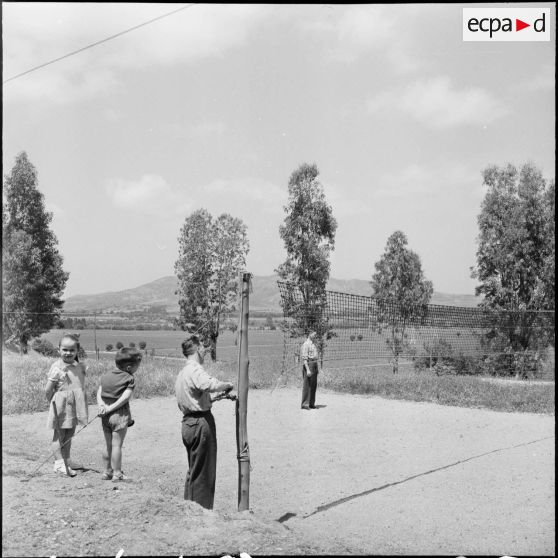 Deux soldats et deux enfants devant un filet de volley-ball.