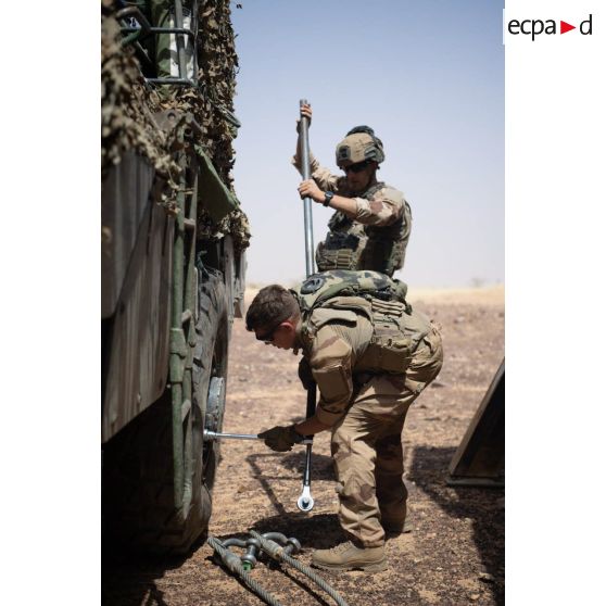 Des soldats du groupement tactique désert (GTD) Bison fixent une nouvelle roue sur leur véhicule de l'avant blindé (VAB) dans le Gourma malien.