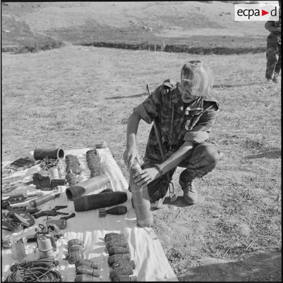 Un béret bleu examine un obus de 165 mm capturé aux rebelles.