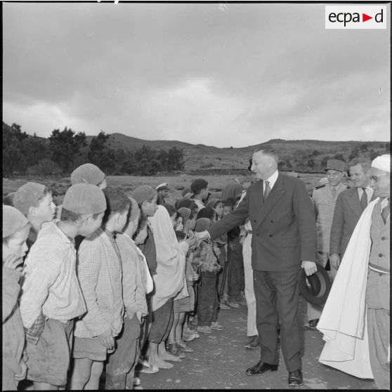 André Morice, ministre de la Défense nationale et des Forces armées, serre la main des enfants de l'école de Boudjima.