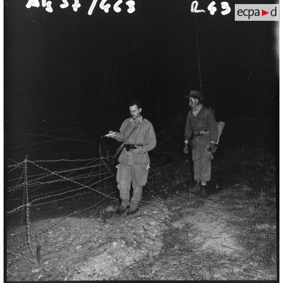 Patrouille de nuit dans le réseau électrifié. Le sous-lieutenant Coppola de la 9ème compagnie du 3/60ème régiment d'infanterie (RI) vérifie les fils barbelés.