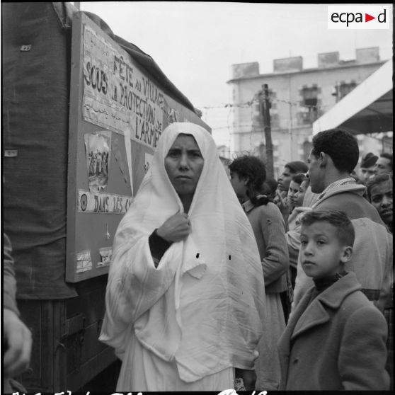 Groupement de population civile devant un camion radio et de propagande.