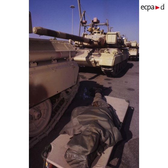 Au pied d'un char lourd de combat AMX-30 B2 du 4e RD (régiment de dragons) sur le port de Yanbu, un soldat se repose sur un lit de camp.