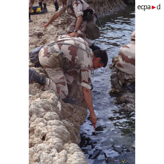 Un adjudant photographe de l'ECPA (Etablissement cinématographique et photographique des Armées) trempe dans le fleuve Euphrate son brassard ECPA.