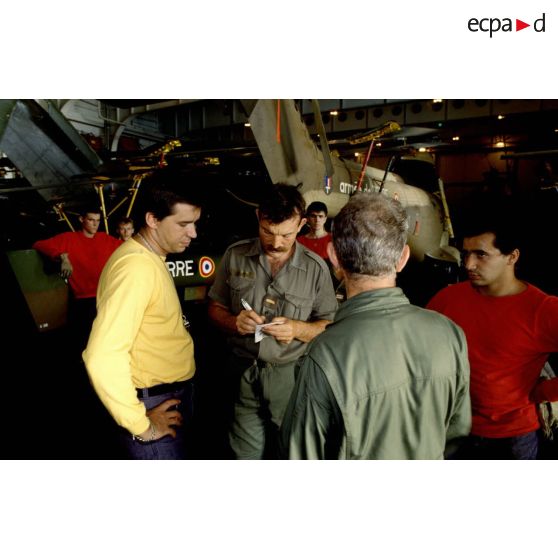 Mécaniciens du 5e RHC et personnels de pont dont un chien jaune dans le hangar du PA (porte-avions) Clemenceau.