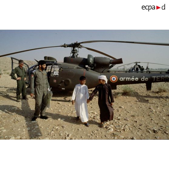 Pilotes français et émiratis avec des enfants émiratis, devant un hélicoptère de combat Gazelle de l'ALAT (aviation légère de l'armée de terre).