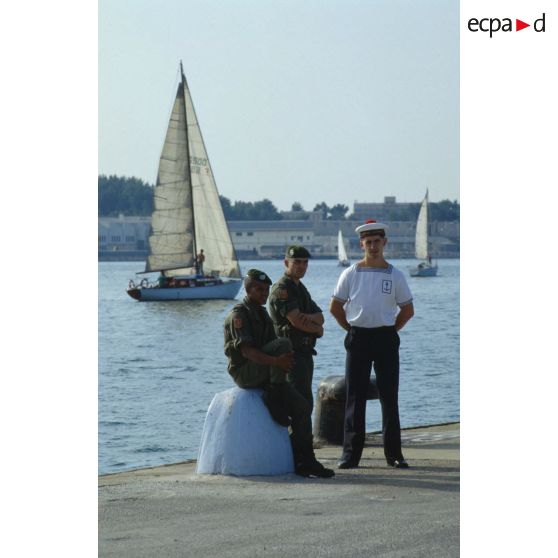 Attente avant l'embarquement sur le ferry affrété Girolata, sur le bord du quai pour un marin et deux légionnaires.