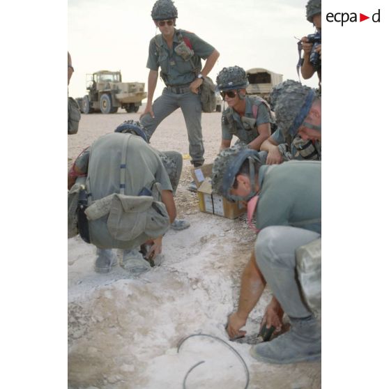 Des soldats du génie enfouissent des pains de plastic dans le sable et posent des mèches lentes pour préparer un fourneau d'explosion lors d'un entraînement au tir à l'explosif.