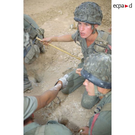 Des soldats du génie enfouissent des pains de plastic dans le sable et posent des mèches lentes pour préparer un fourneau d'explosion lors d'un entraînement au tir à l'explosif.