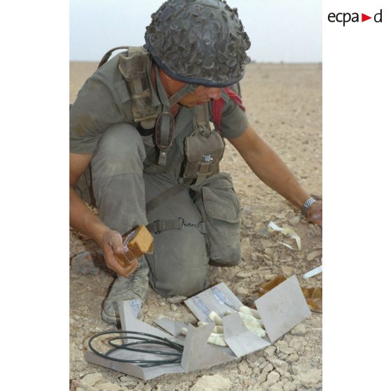 Un soldat du génie manipule des pains de plastic à enfouir dans le sable et des mèches lentes pour préparer un fourneau d'explosion lors d'un entraînement au tir à l'explosif.