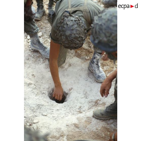 Des soldats du génie enfouissent des pains de plastic dans le sable pour préparer un fourneau d'explosion lors d'un entraînement au tir à l'explosif.