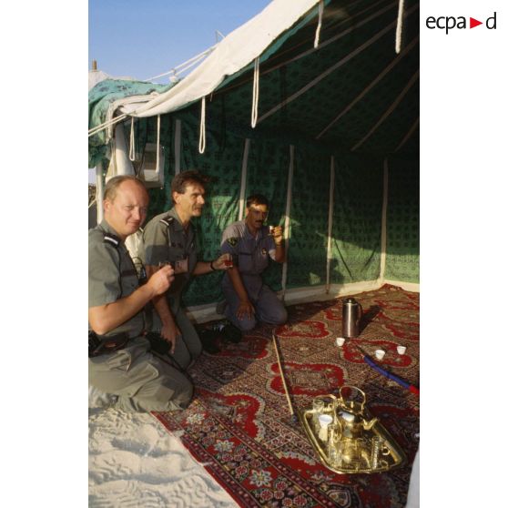 Sous une tente saoudienne, des aviateurs français de la BA (base aérienne) d'Al Ahsa et des membres de l'équipe de l'ECPA (Etablissement cinématographique et photographique des Armées) boivent le thé offert par les bédouins.