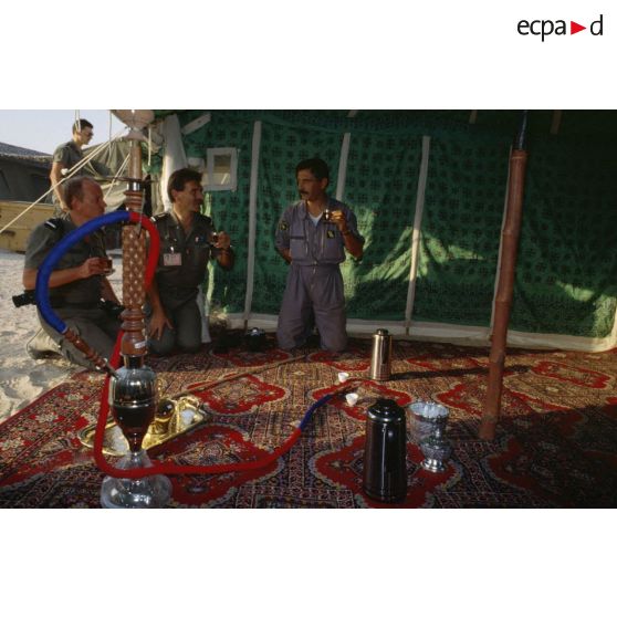 Sous une tente saoudienne, des aviateurs français de la BA (base aérienne) d'Al Ahsa et des membres de l'équipe de l'ECPA (Etablissement cinématographique et photographique des Armées) boivent le thé offert par les bédouins.