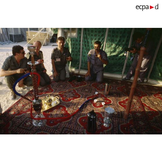 Sous une tente saoudienne, des aviateurs français de la BA (base aérienne) d'Al Ahsa et des membres de l'équipe de l'ECPA (Etablissement cinématographique et photographique des Armées) boivent le thé offert par les bédouins.