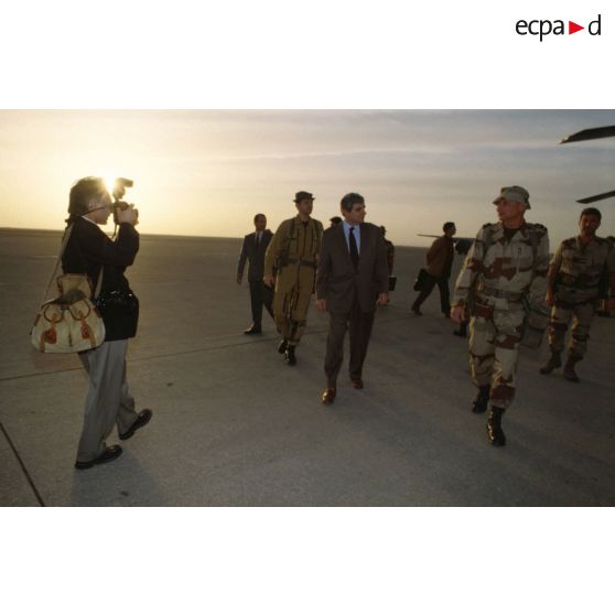 Jean-Pierre Chevènement, ministre de la Défense, à sa descente d'avion sur l'aéroport de CRK (camp du roi Khaled), accompagné son photographe de l'ECPA (Etablissement cinématographique et photographique des Armées), est accueilli par le général de brigade Jean-Charles Mouscardès, commandant la division Daguet.