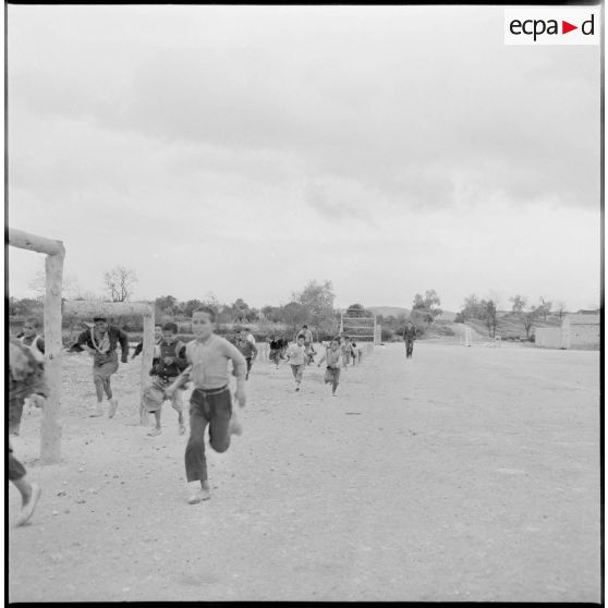 Des enfants font un parcours sportif, sous le regard d'un militaire.