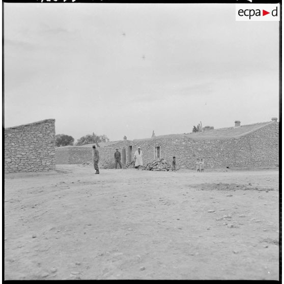 Des hommes et des enfants devant des maisons.