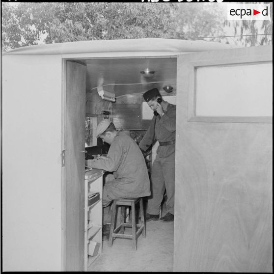 Soldats au travail dans un camion aménagé en bureau.