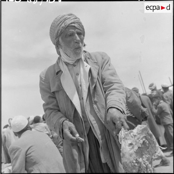 Un homme mange un morceau de viande du méchoui.