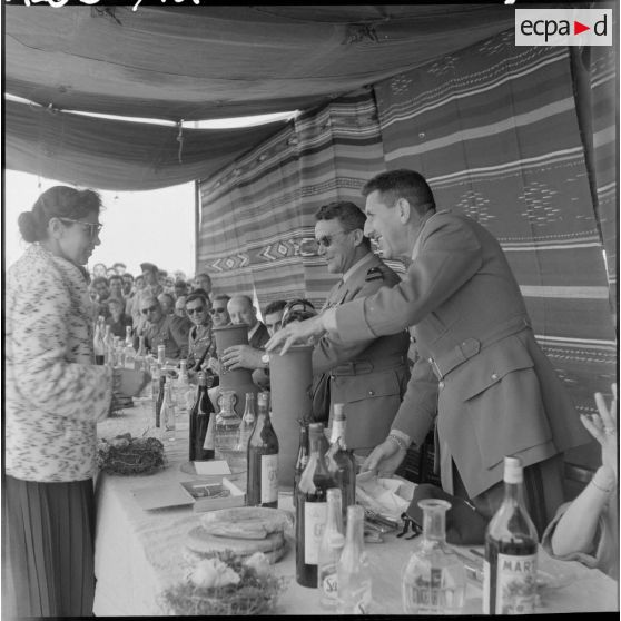 A la table du banquet, le général Jacques Massu et une autorité s'entretiennent avec une femme.