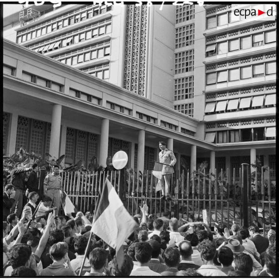 Le colonel Ducournau, monté sur la grille du palais du gouvernement général, tente de parler aux manifestants qui veulent l'envahir.