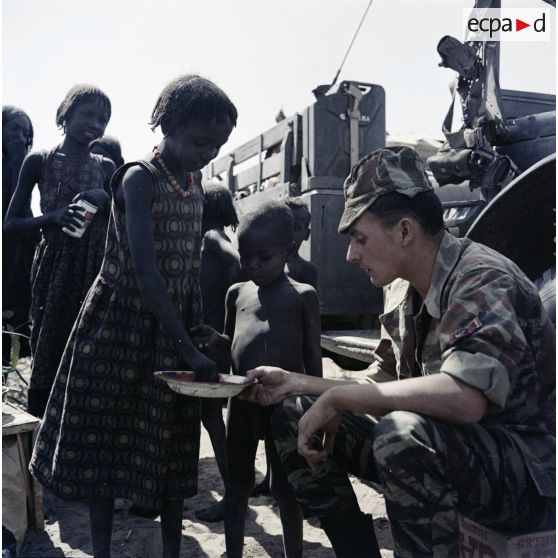 Un soldat français partage son repas avec des enfants tchadiens pendant une halte.