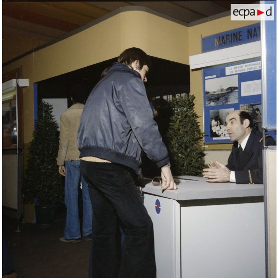 Un homme accueille un étudiant sur le stand de l'exposition Jeunesse 1976, dans l'ancienne gare de la Bastille à Paris.