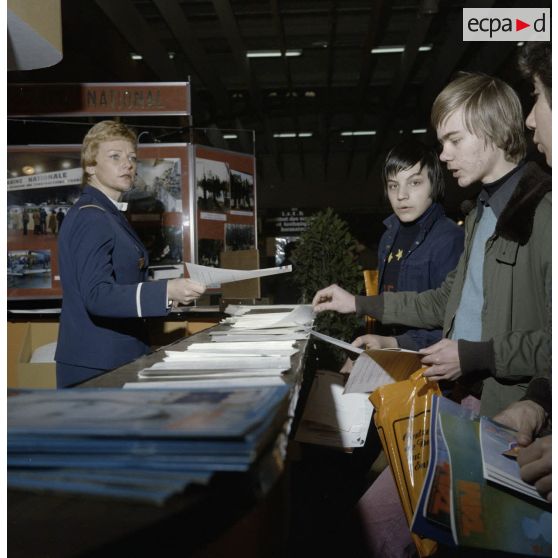 Une hôtesse distribue de la documentation à des étudiants sur un espace du stand de l'exposition Jeunesse, dans l'ancienne gare de la Bastille à Paris.