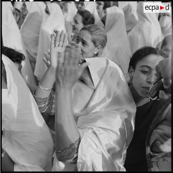 Une femme applaudit parmi la foule, lors d'une grande manifestation en l'honneur des femmes au forum d'Alger.