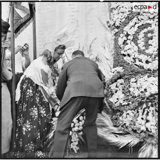 Une femme en costume traditionnel dépose une gerbe de fleurs au monument aux morts d'Alger.