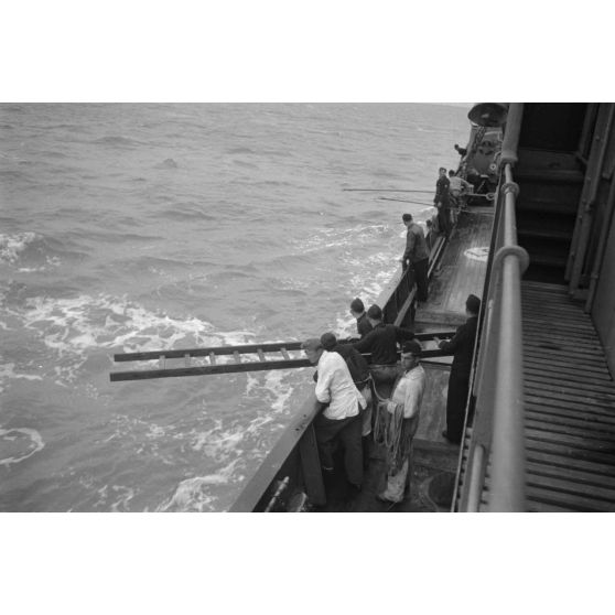 Depuis un dragueur de mines (Minensuchboot), un marin allemand récupère une bouée de sauvetage tombée à la mer.