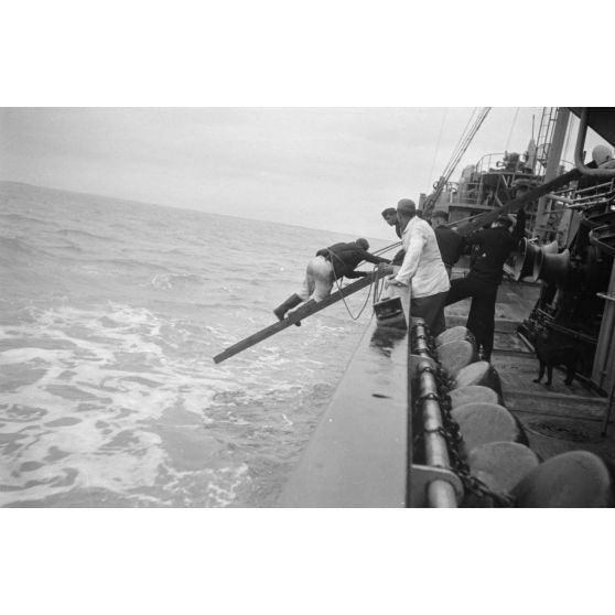 Depuis un dragueur de mines (Minensuchboot), un marin allemand récupère une bouée de sauvetage tombée à la mer.