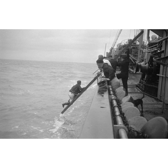 Depuis un dragueur de mines (Minensuchboot), un marin allemand récupère une bouée de sauvetage tombée à la mer.