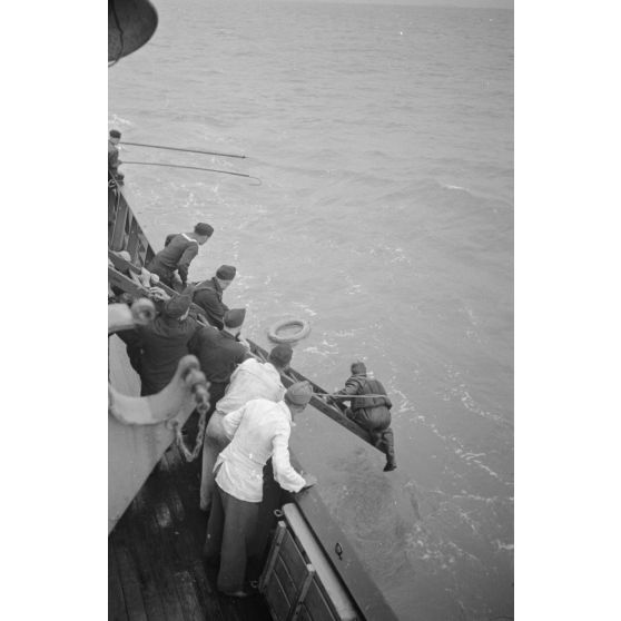 Depuis un dragueur de mines (Minensuchboot), un marin allemand récupère une bouée de sauvetage tombée à la mer.