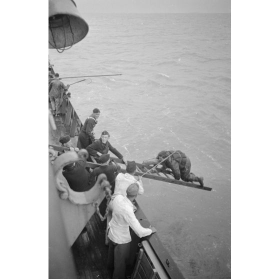 Depuis un dragueur de mines (Minensuchboot), un marin allemand récupère une bouée de sauvetage tombée à la mer.