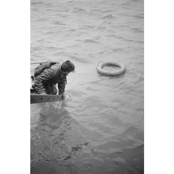 Depuis un dragueur de mines (Minensuchboot), un marin allemand récupère une bouée de sauvetage tombée à la mer.