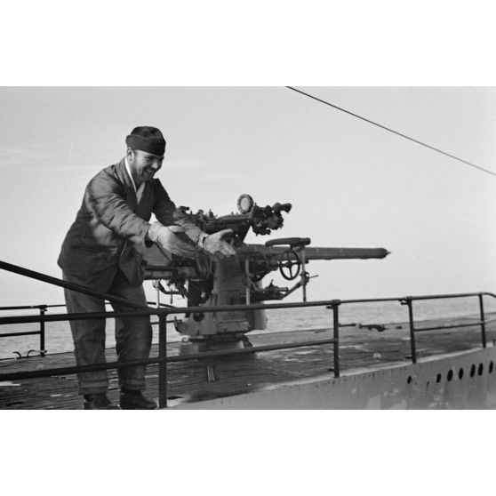 A bord d'un navire léger, non loin du port de Saint-Nazaire, des marins se rapprochent du sous-marin U-552 pour leur offrir des cadeaux, le canon de bord du sous-marin.