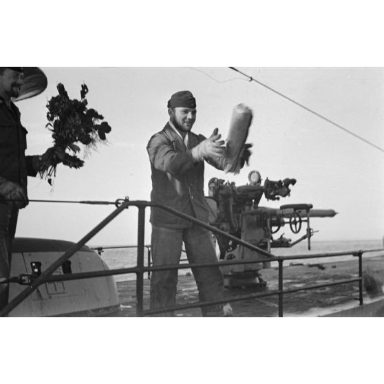 A bord d'un navire léger, non loin du port de Saint-Nazaire, des marins se rapprochent du sous-marin U-552 pour leur offrir des cadeaux, le canon de bord du sous-marin.