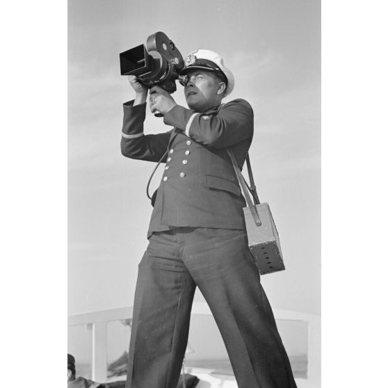 A bord d'un navire léger, non loin du port de Saint-Nazaire, un cameraman équipé de son Arriflex 35 mm filme le retour du sous-marin U-552 (non visible).