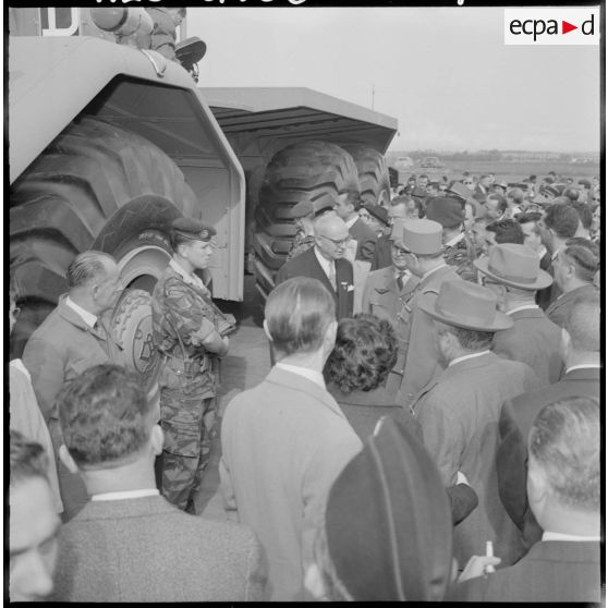 Des autorités civiles et militaires visitent une chaîne de montage de véhicules.