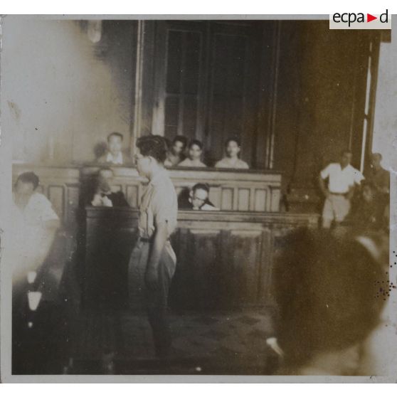 Dans la salle du palais de justice où se tient le procès des criminels de guerre japonais, un homme se tient debout.