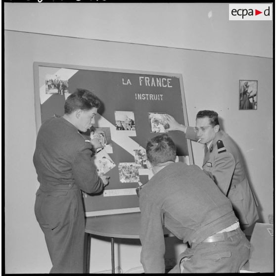 Algérie. 5e bureau. Des stagiaires officiers placent des photos sur l'affiche de propagande.