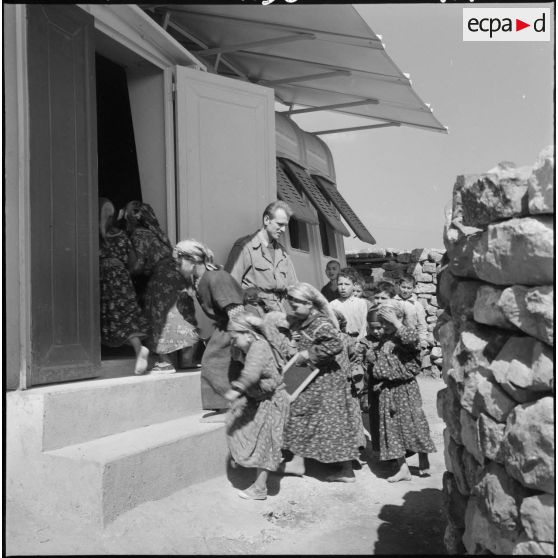 Un soldat instituteur à Boudjima surveille les élèves entrant dans la classe.