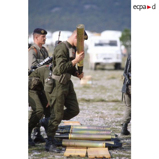 Marsouin du 1er régiment d'infanterie de marine (1er Rima) ayant ramassé un obus préparé au sol pour aller le charger dans un véhicule blindé ERC-90 Sagaie.