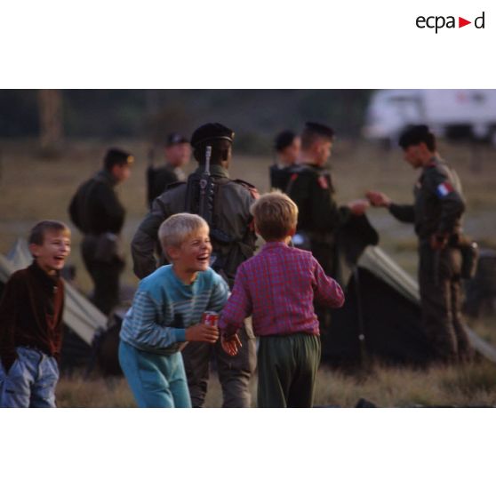 Enfants croates jouant à côté des militaires français au campement installé sur l'autodrome de Rijeka.