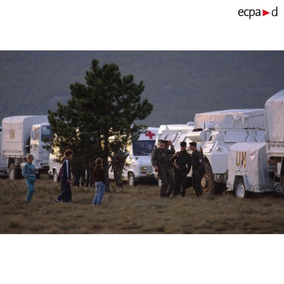 Enfants croates curieux s'approchant des casques bleus du bataillon français rassemblés sur l'autodrome de Rijeka près de leurs véhicules.