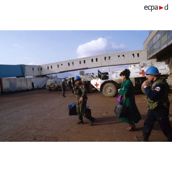 Femme et bébé escortés par des casques bleus lors de l'évacuation de blessés légers et de malades civils vers la France sur l'aéroport de Sarajevo.