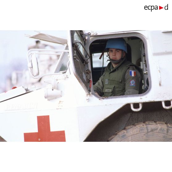 Portrait d'un conducteur de véhicule de l'avant blindé (VAB) sanitaire à son poste de pilotage, portière ouverte, arborant casque bleu et insigne de la 11e brigade parachutiste.