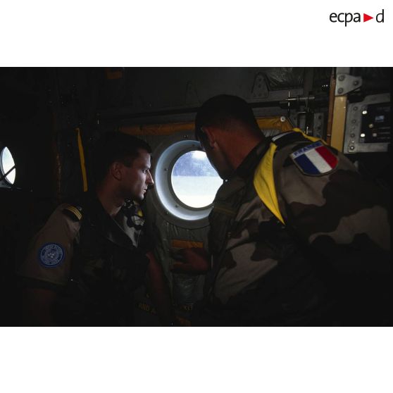 Un capitaine et un adjudant du 14e régiment parachutiste de commandement et de service (14e RPCS) regarde par le hublot d'un avion Hercules C-130.