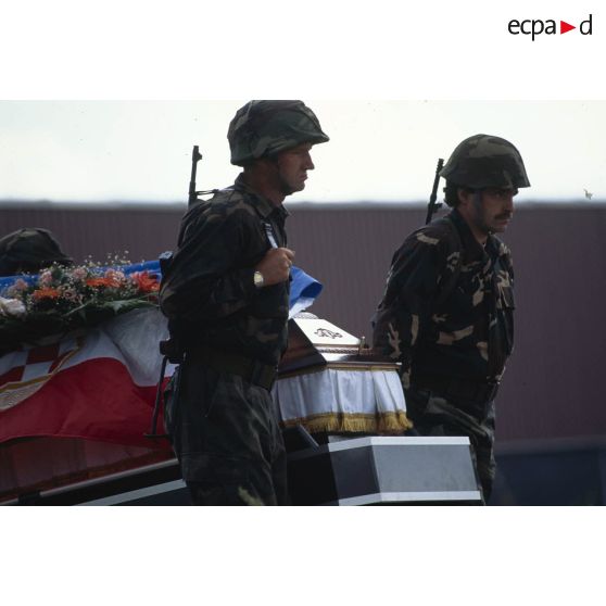 Deux militaires croates de Bosnie entourent un cercueil couvert d'un drapeau croate lors d'une levée de corps à Trogir, sur le camp ONU du détachement de l'aviation légère de l'Armée de terre (DETALAT).